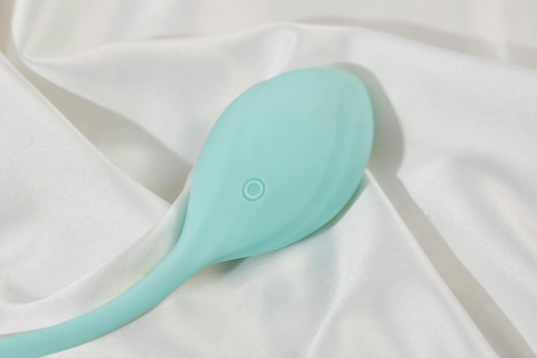 Ein türkisfarbener Zitronenvibrator auf weißer Seide, elegant arrangiert