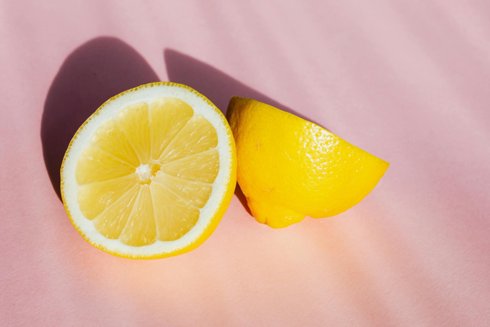 Frische Zitronenhälften auf rosa Hintergrund in Sonnenlicht