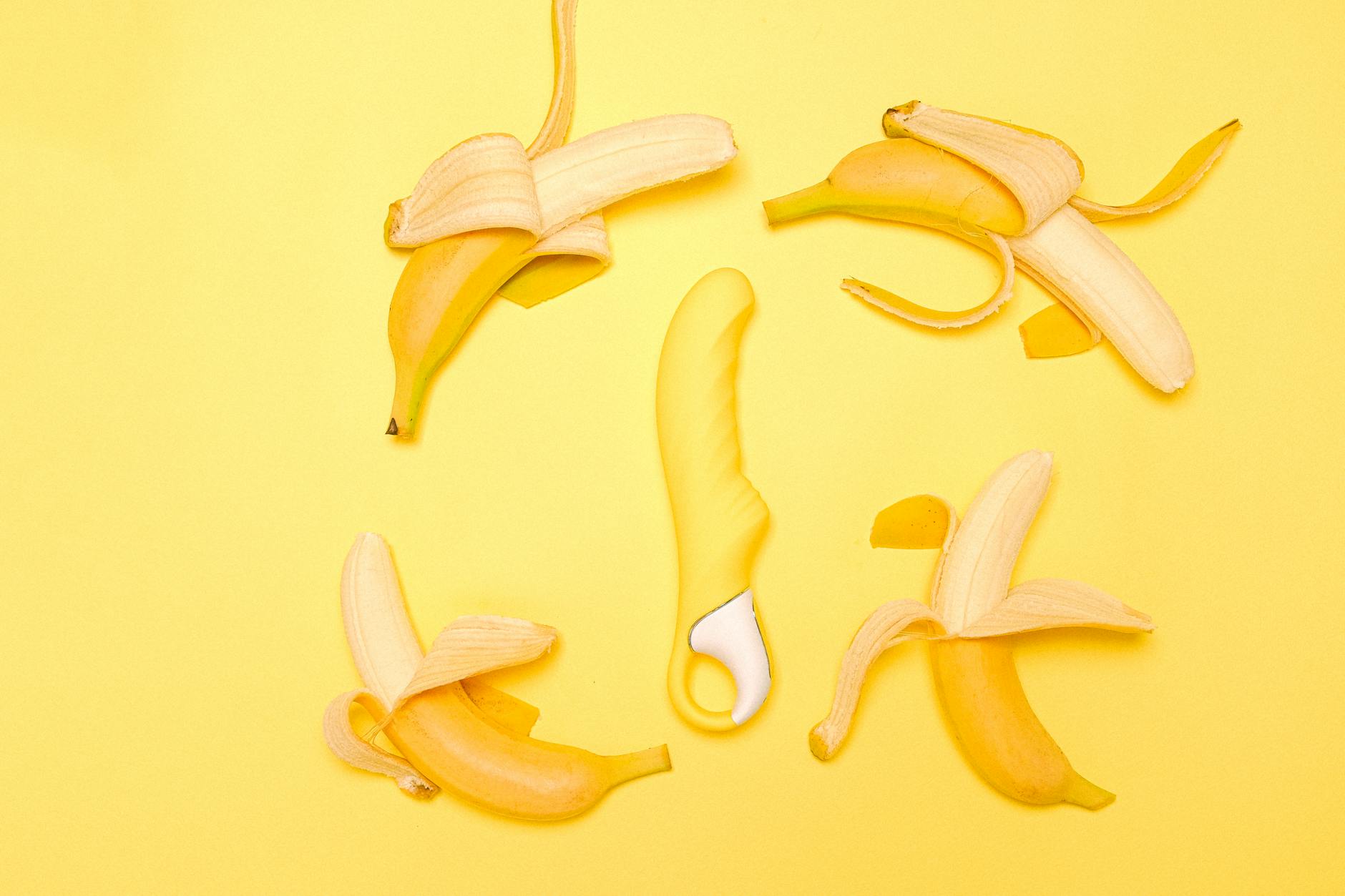 Gelber Zitronenvibrator umgeben von geschälten Zitronenhälften auf gelbem Hintergrund
