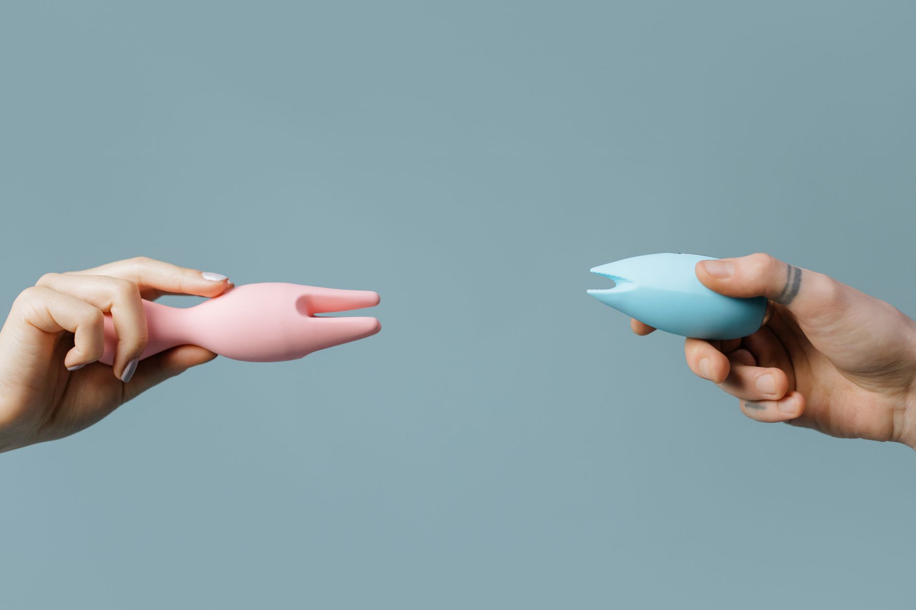 Ein junges Paar steht zusammen und hält einen blauen Vibrator, ein Symbol für moderne Intimität zwischen Partnern.