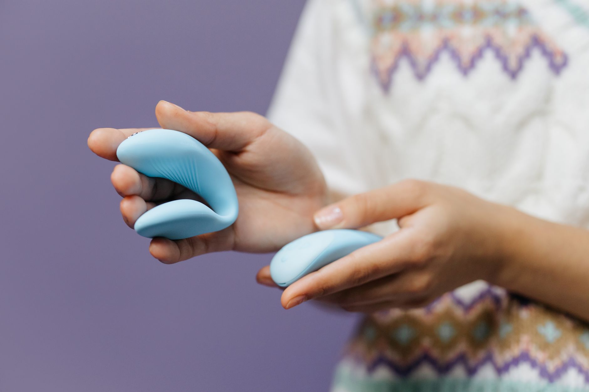 Nahaufnahme einer Hand, die einen eleganten blauen Zitronensauger gegen lila Hintergrund hält.